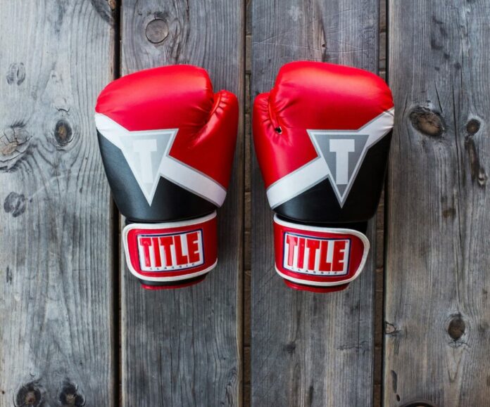 Spribe-UFC-Partnership Two UFC gloves on a wooden canvas.